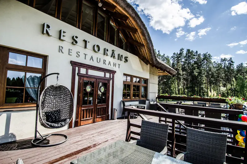 Restorāna ieeja un terase ar priedēm