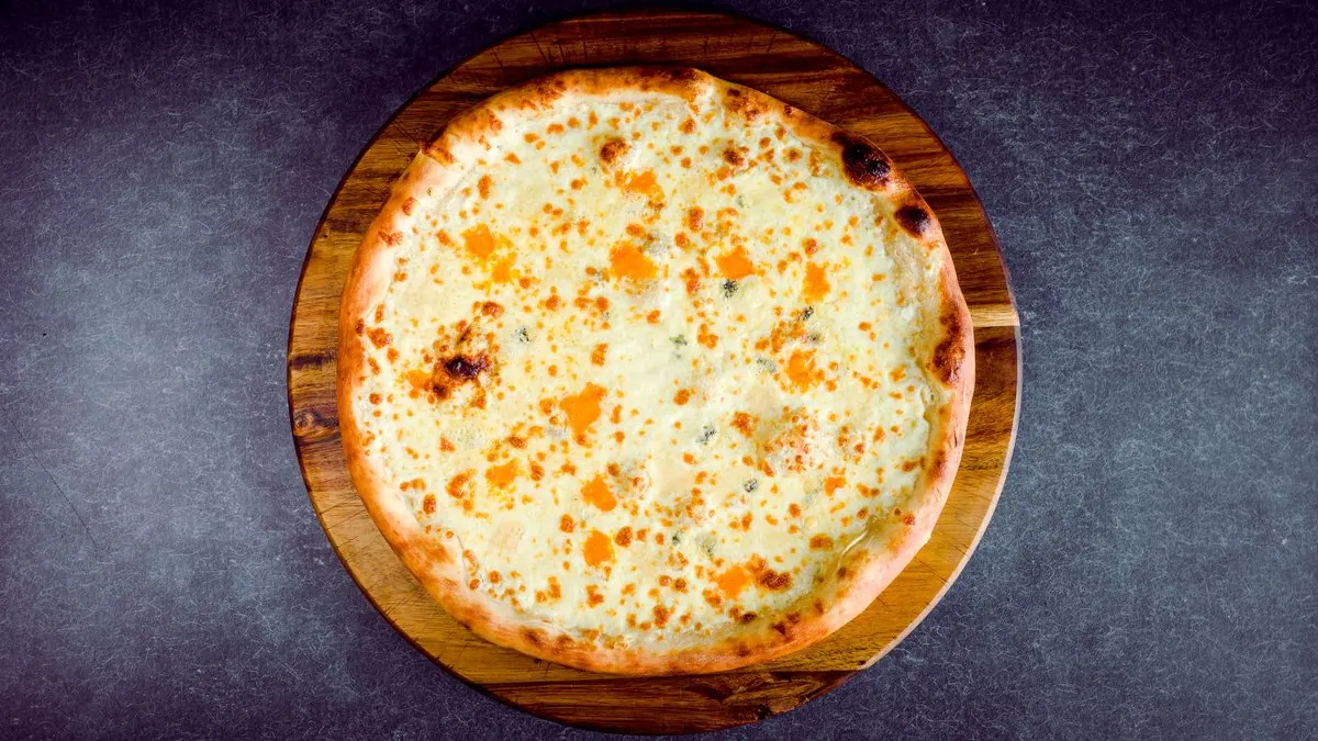 Quattro formaggi pizza on a wooden board