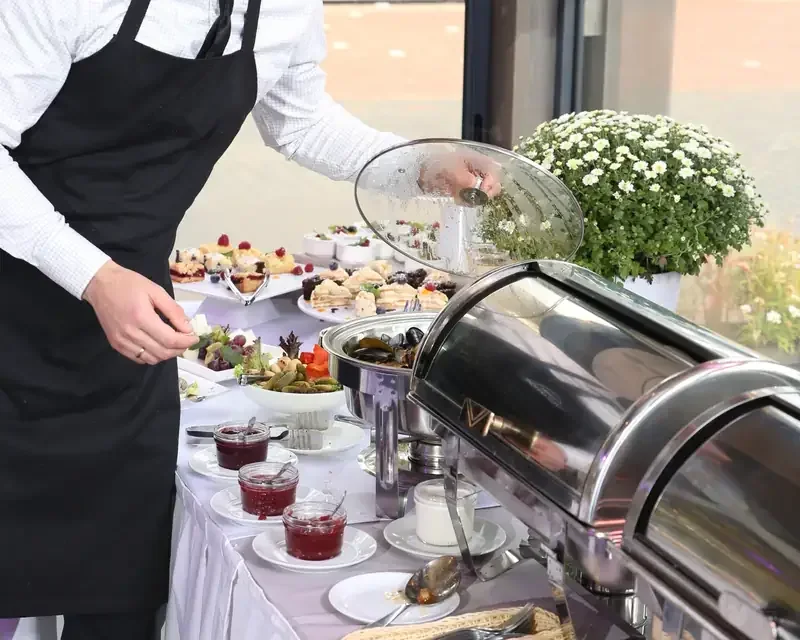 Viesmīlis pie bufetes galda ar ziediem
