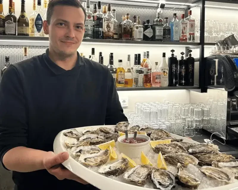 Restorāna darbinieks ar pasniedzamo šķīvi pie bāra